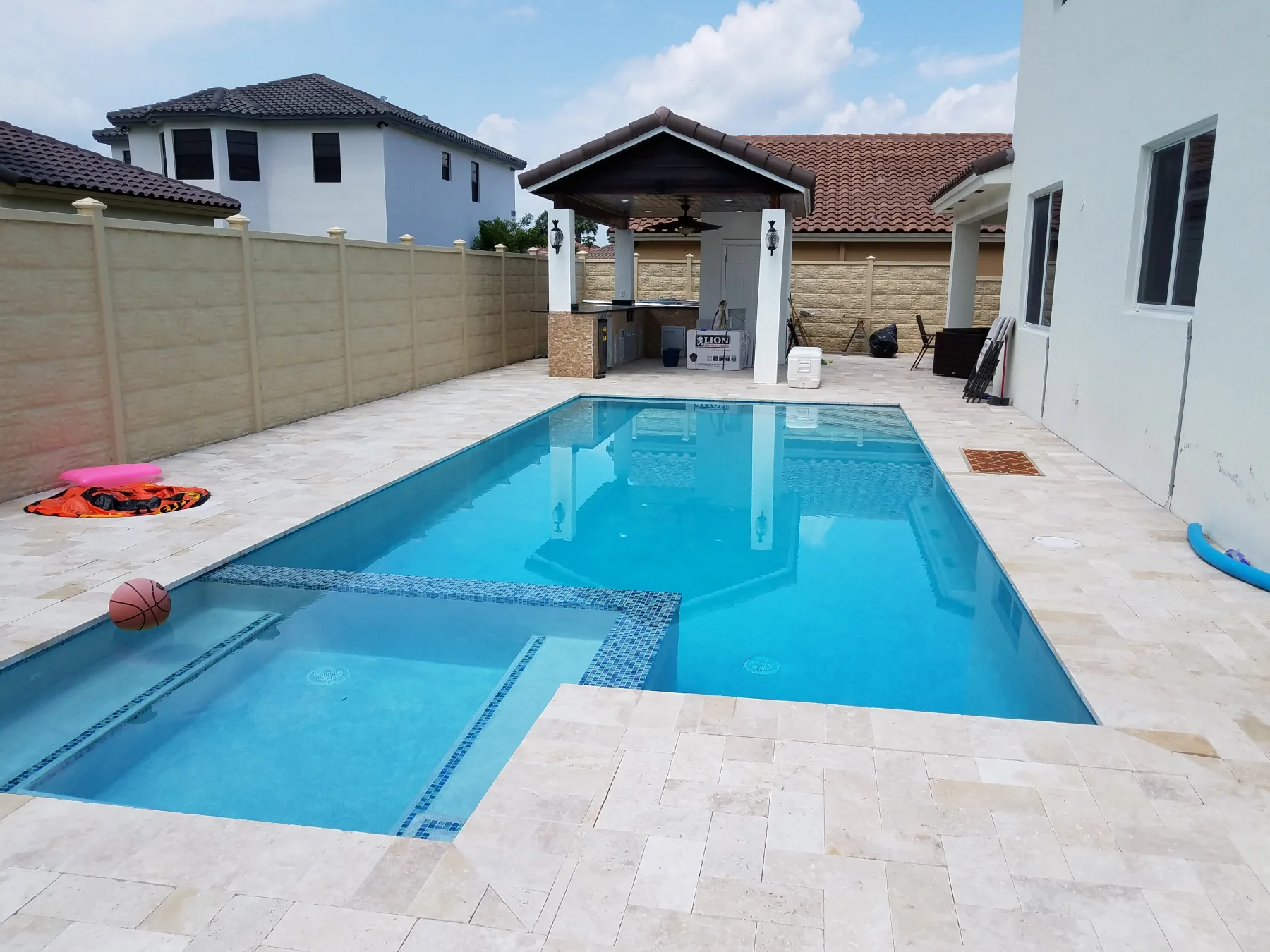 Rectangular swimming pool with raised spa and pale stone patio