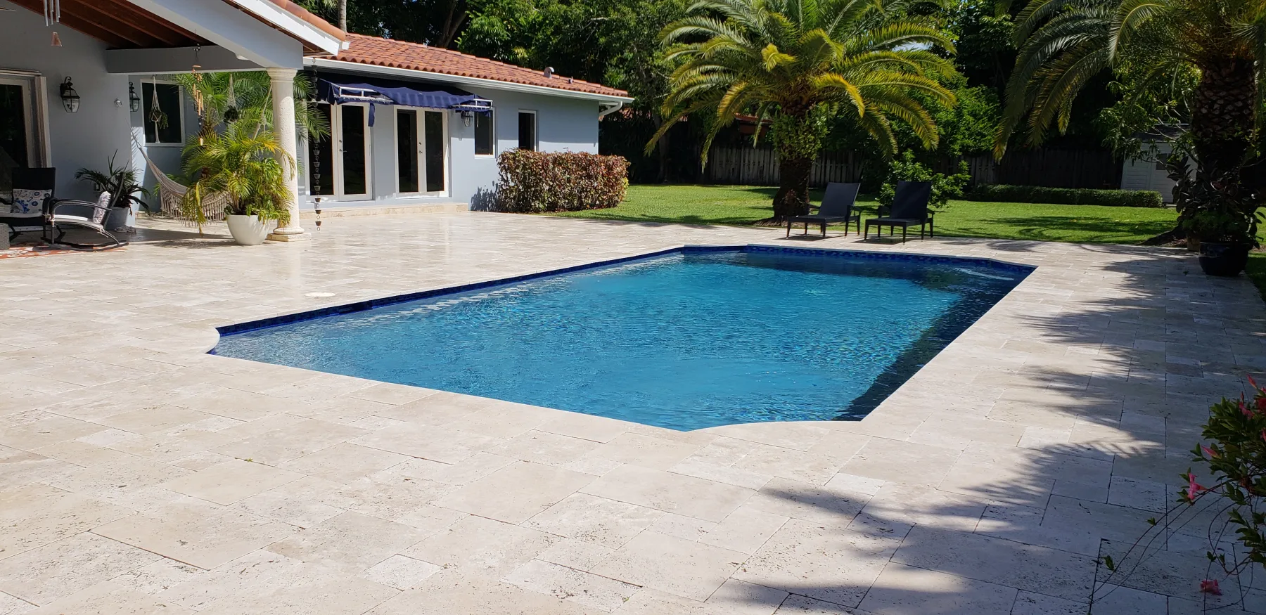 Wide stone patio surrounding a rectangular pool