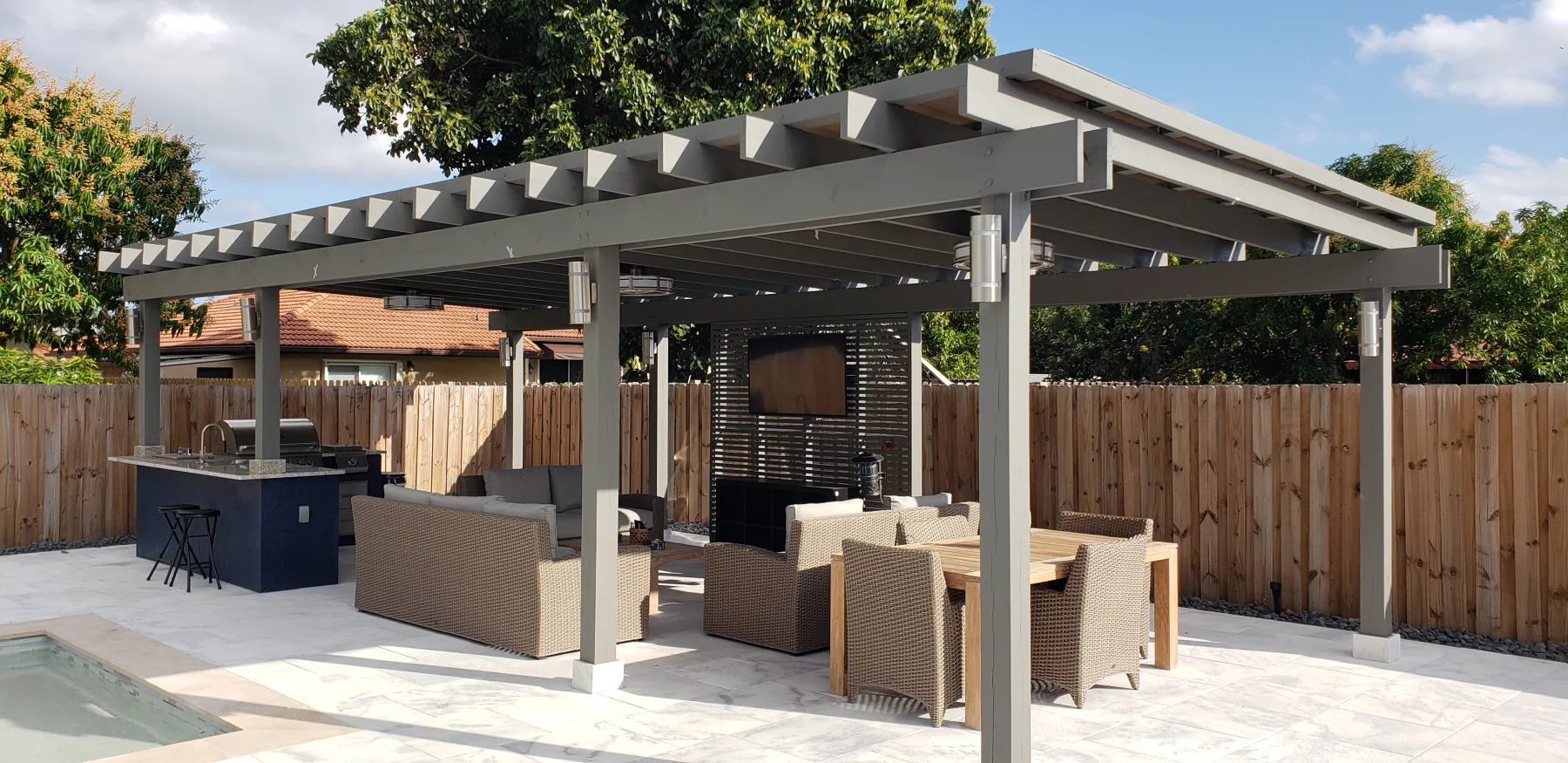 Gray pergola framing an outdoor kitchen and dining space