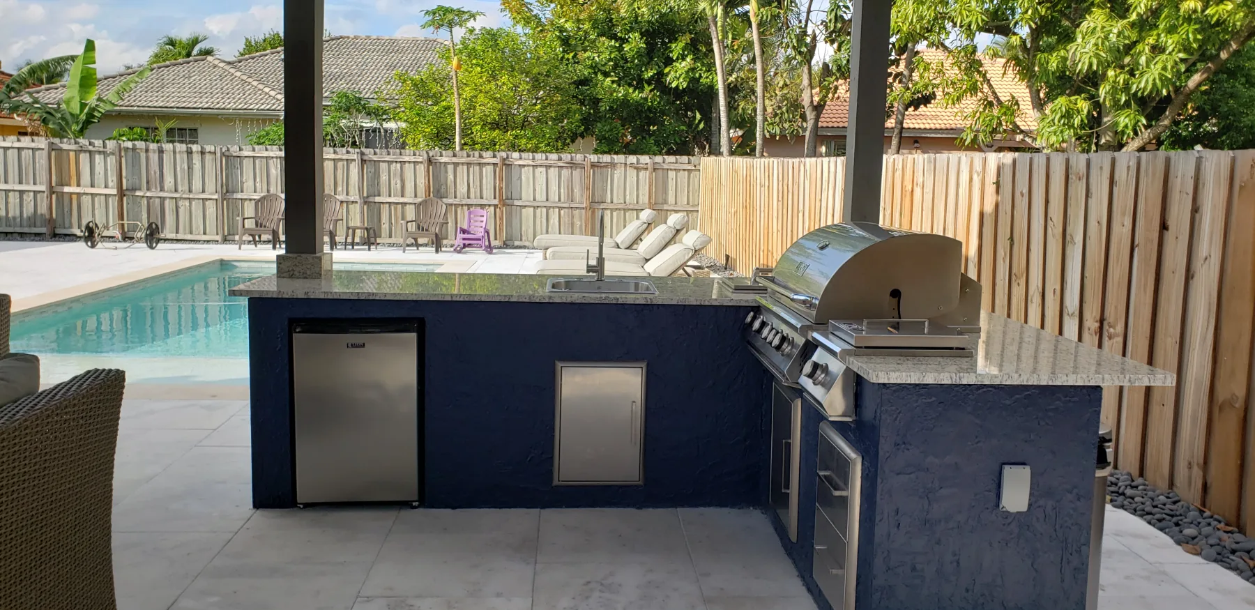Blue outdoor kitchen island beside the pool