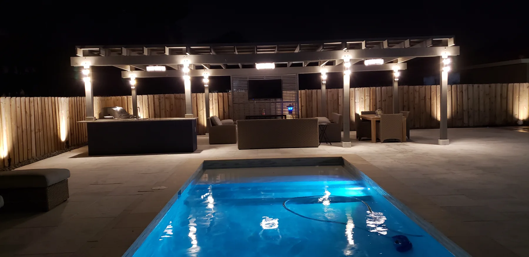 Illuminated pool and outdoor kitchen at night
