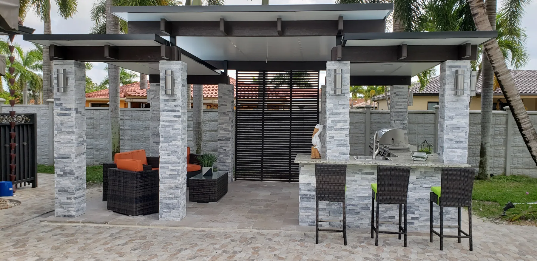 Stone outdoor kitchen and pergola with bar seating
