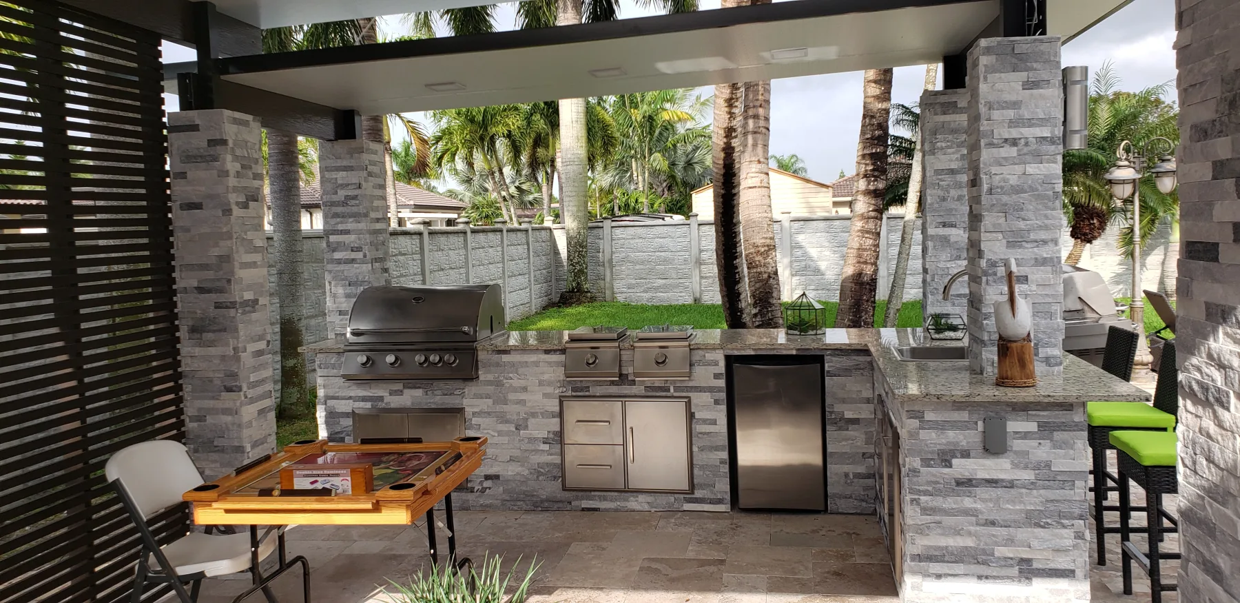 Outdoor kitchen with stone columns and a covered seating area