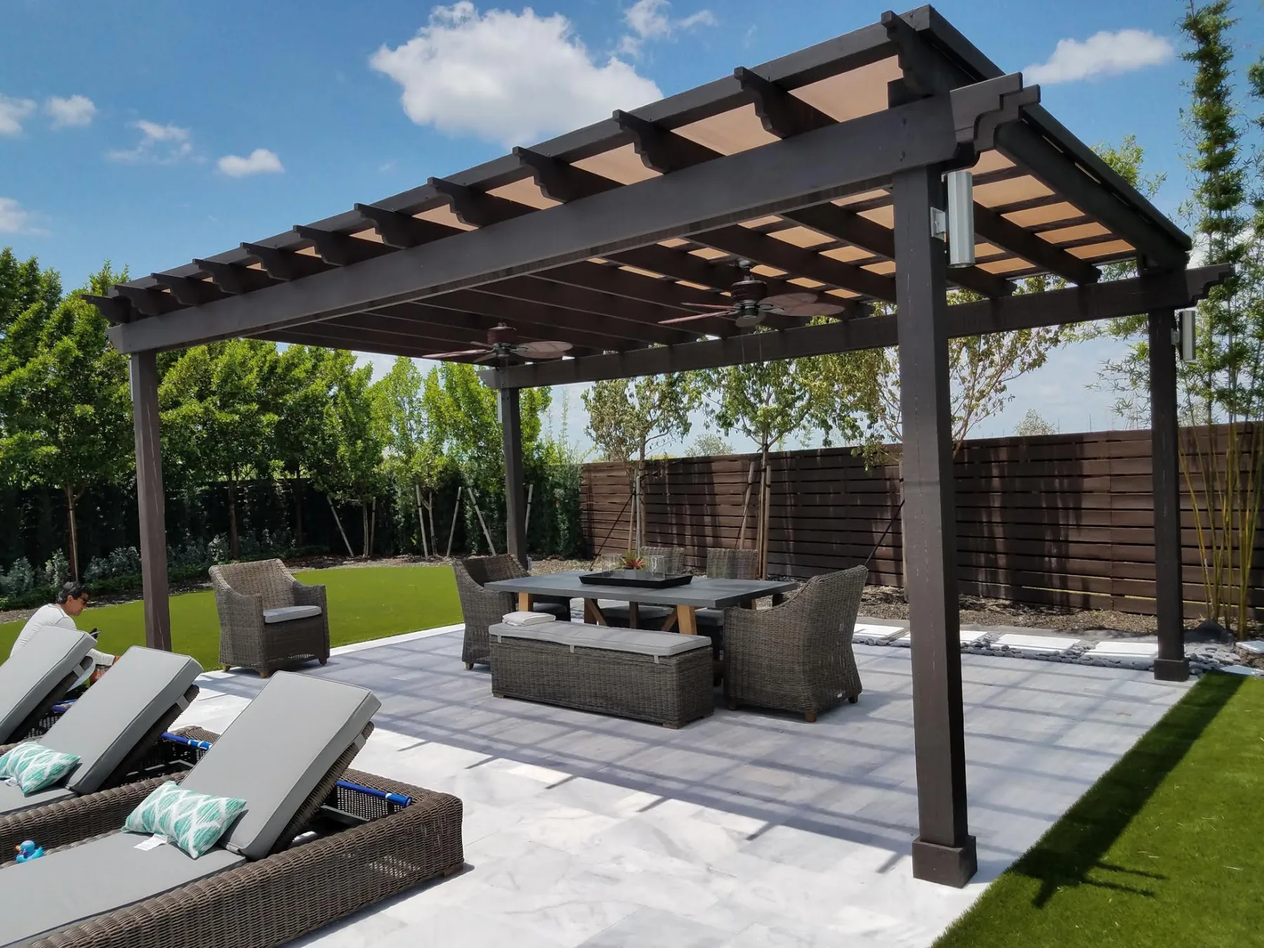 Wood pergola and seating beside a synthetic turf lawn