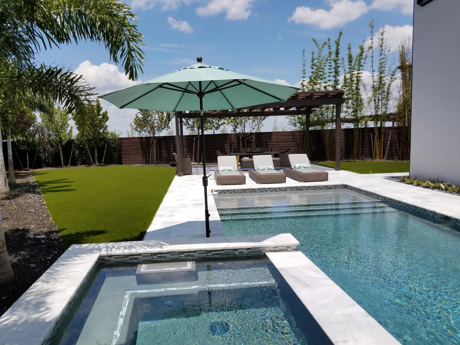 Pool and spa next to a landscaped lawn and pergola